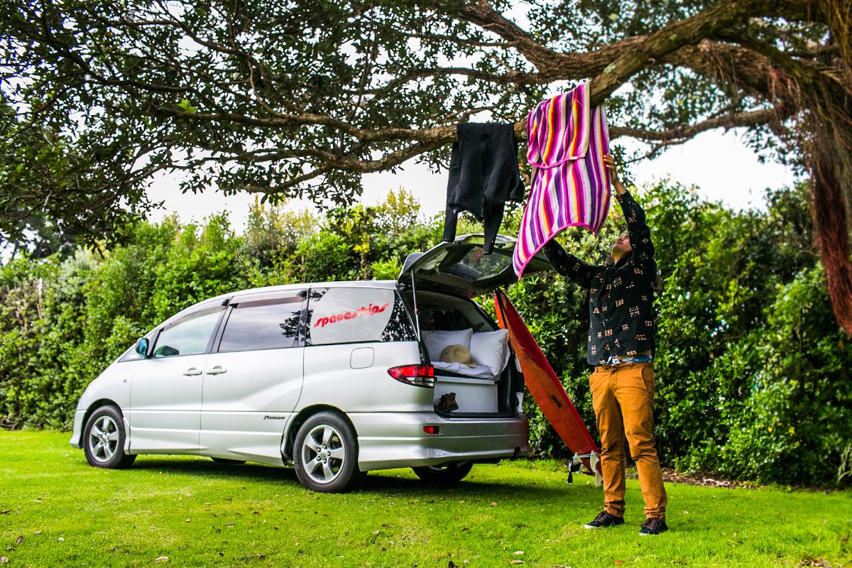 Man hanging his wet towels on the tree at his campground next to his campervan