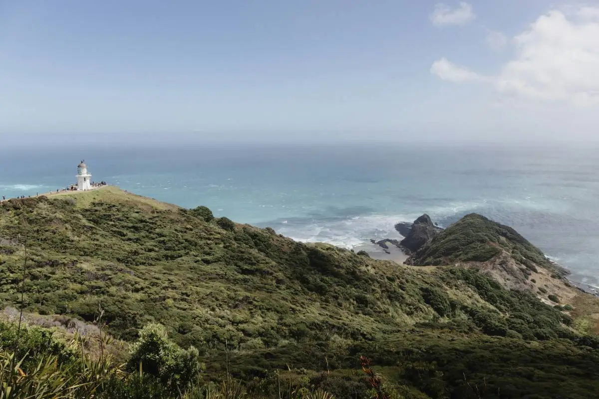 Coastal headlands with a lighthouse on the far left and the blue ocean in the background