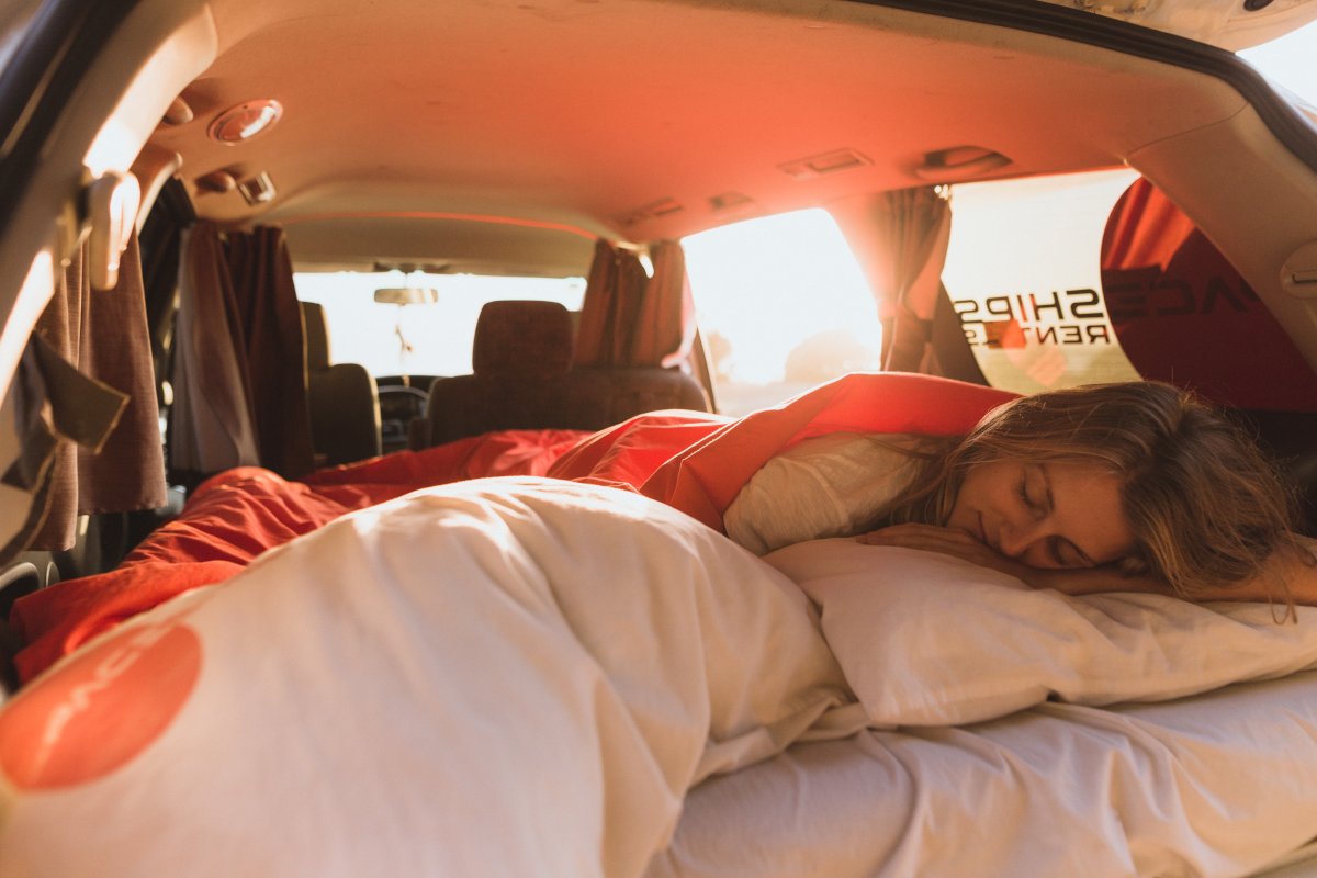 Woman sleeping in her campervan as the sun comes up
