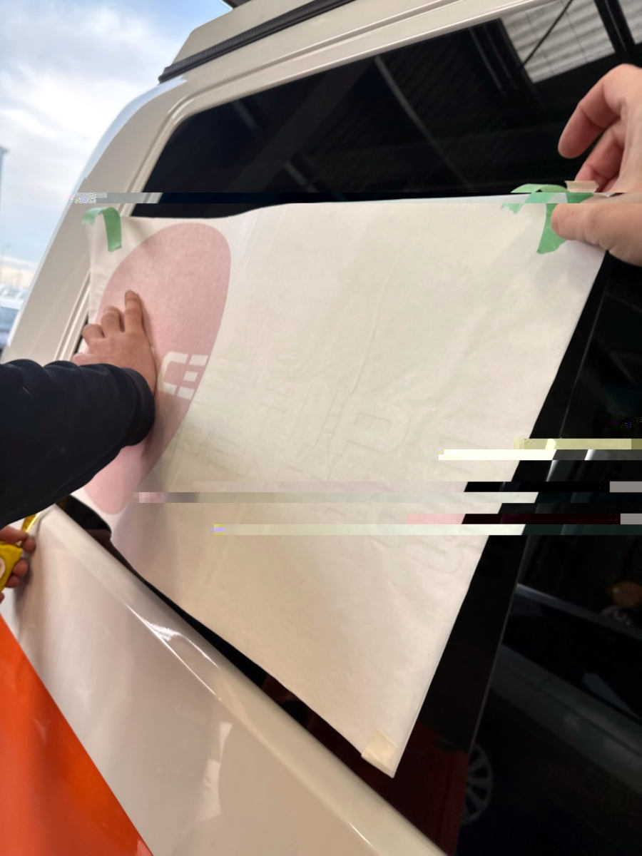 Close up of two hands applying stickers to a campervan
