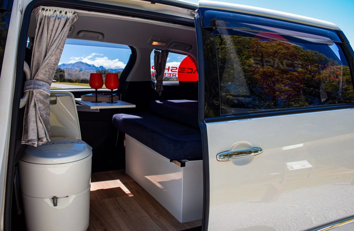 Interior of a campervan with a built in toilet and adjustable table